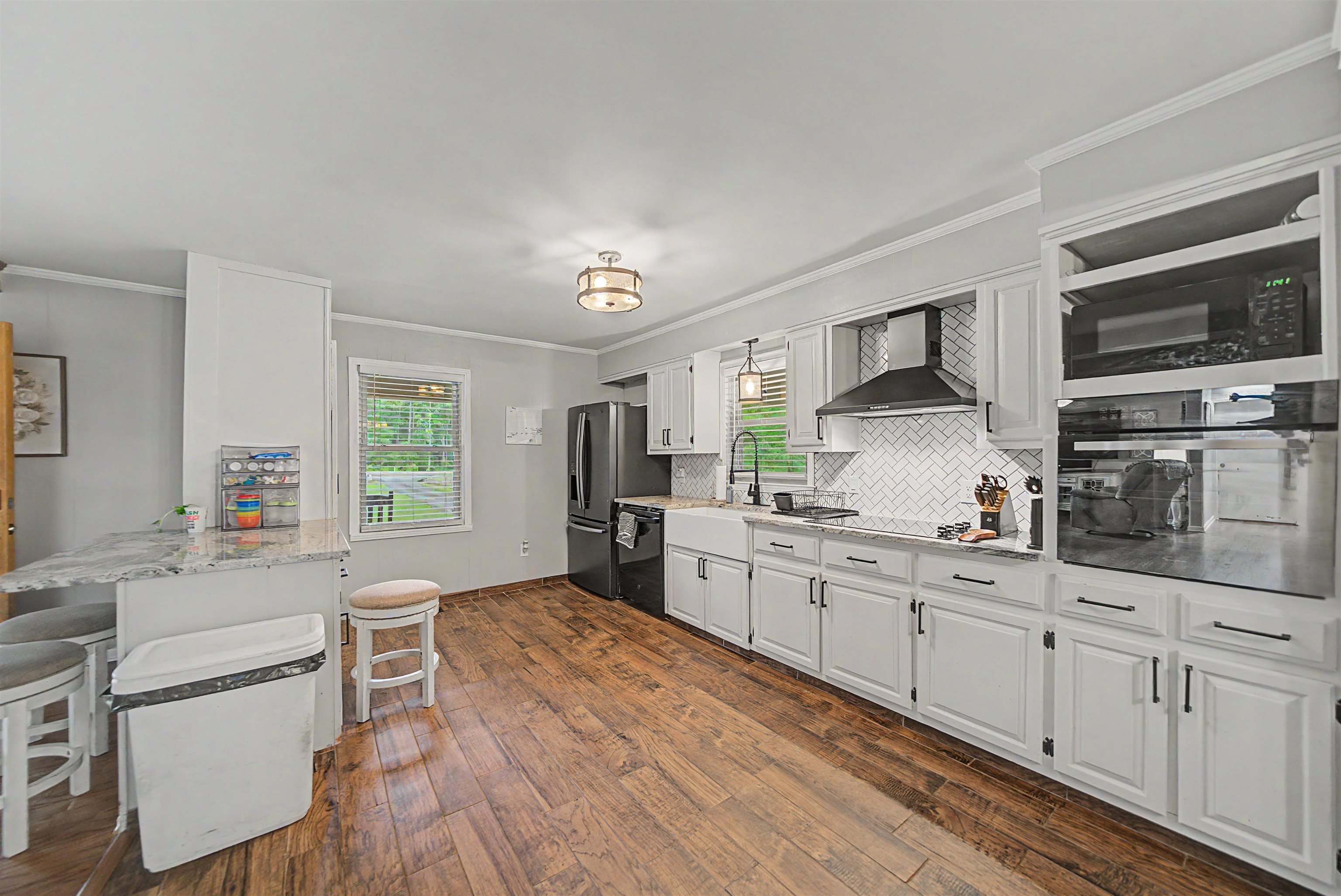 336 57th Highway West Ramer, TN 38367 - Photo 15 of 39 Kitchen featuring wood-finish flooring, white cabinetry with dark hardware, a herringbone pattern tile backsplash, and built-in appliances