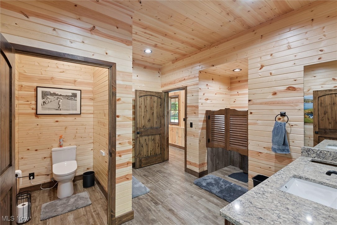 290 Townline Road Aurora, OH 44202 - Photo 33 of 50 Bathroom with light wood-type flooring, wood walls, double vanity, wooden ceiling, and recessed lighting