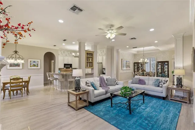 a living room with furniture kitchen view and a chandelier
