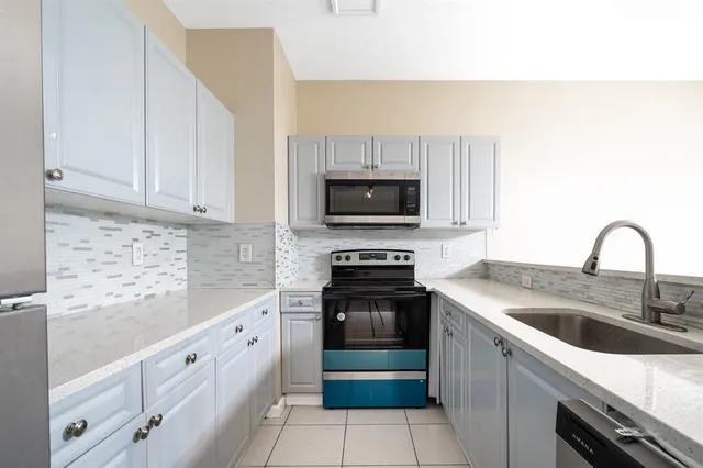 a kitchen with granite countertop white cabinets and stainless steel appliances