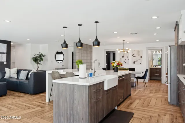 a kitchen with stainless steel appliances kitchen island granite countertop a refrigerator a stove a microwave oven a dining table and chairs with wooden floor