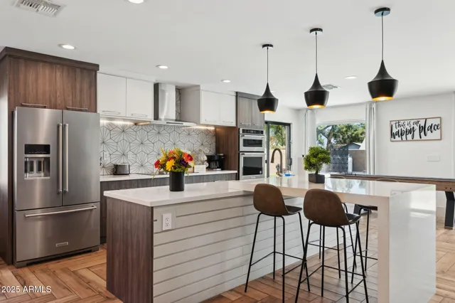 a kitchen with stainless steel appliances kitchen island granite countertop a sink and a flat screen tv