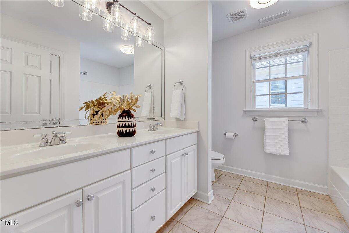 201 Brooks Avenue Raleigh, NC 27607 - Photo 16 of 44 a bathroom with a double vanity sink a toilet and a window