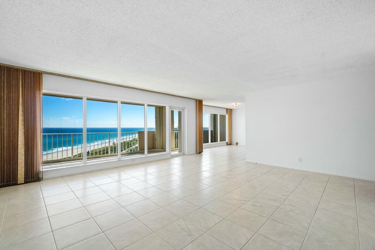 4001 North Ocean Boulevard, Unit 1503 Boca Raton, FL 33431 - Photo 12 of 46 an empty room with floor to ceiling windows and chandelier