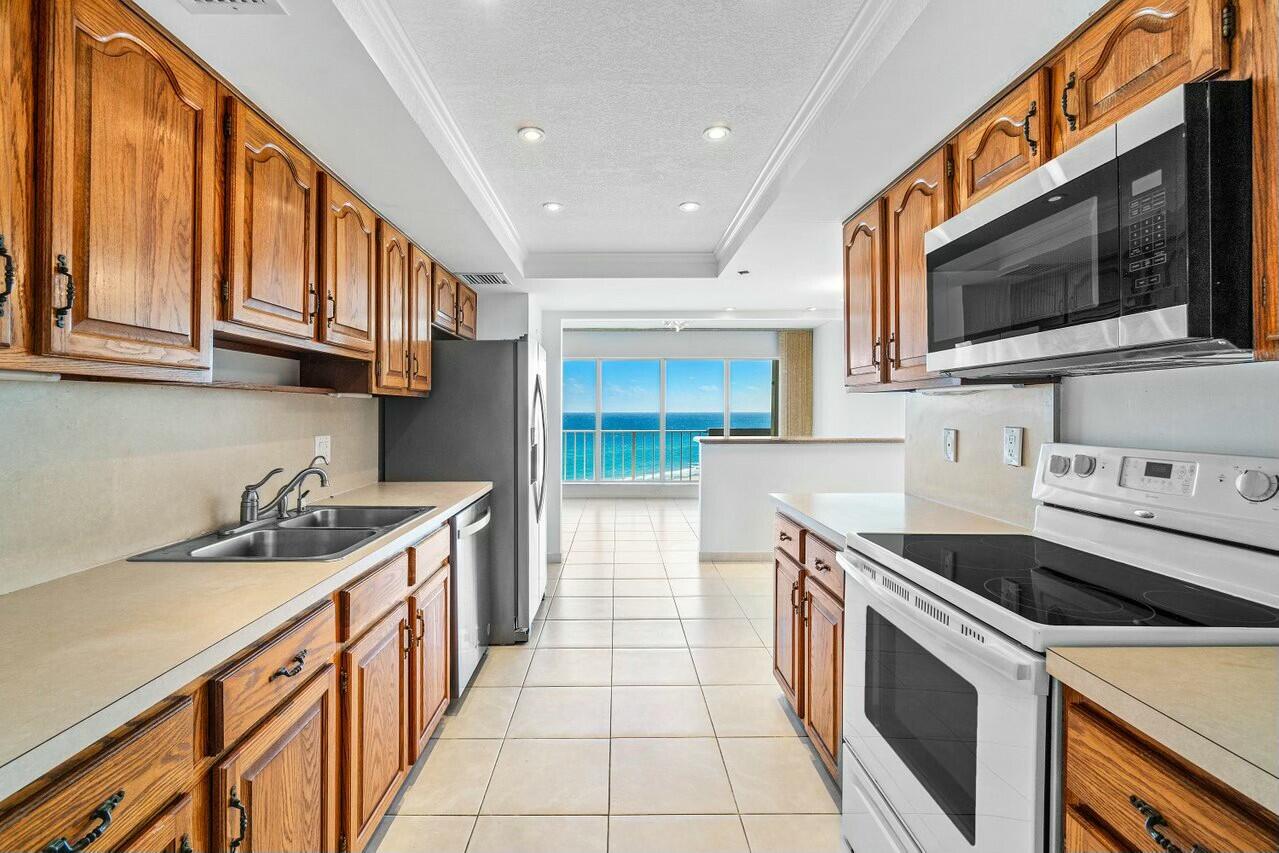 4001 North Ocean Boulevard, Unit 1503 Boca Raton, FL 33431 - Photo 14 of 46 a kitchen with stainless steel appliances a stove a microwave and a sink