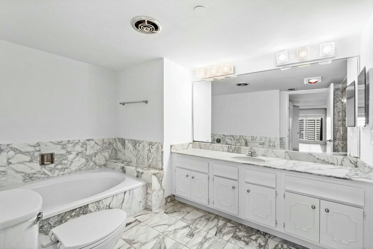 4001 North Ocean Boulevard, Unit 1503 Boca Raton, FL 33431 - Photo 26 of 46 a bathroom with a granite countertop double vanity sink a mirror and a bathtub