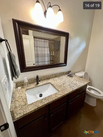 a bathroom with a granite countertop sink a toilet and mirror