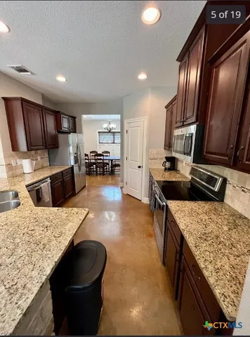 a kitchen with stainless steel appliances granite countertop a sink stove and refrigerator