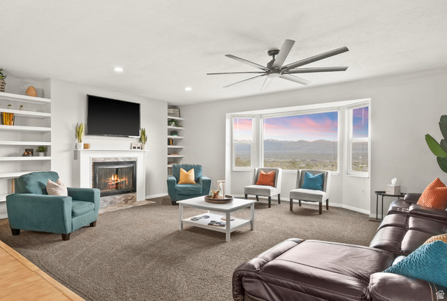 9750 Indian Ridge Drive Sandy, UT 84092 - Photo 9 of 40 Carpeted living area featuring a fireplace with flush hearth, built in shelves, ceiling fan, and recessed lighting