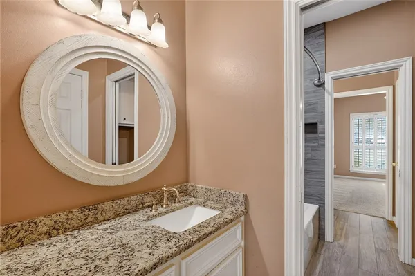 a bathroom with a granite countertop sink and a mirror