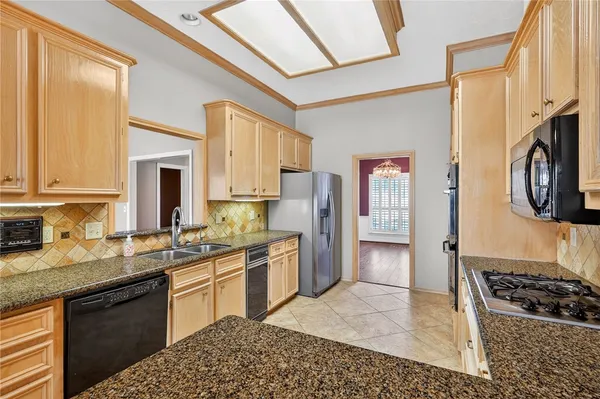 a kitchen with stainless steel appliances granite countertop a stove top oven a sink dishwasher a dining table and chairs with wooden floor