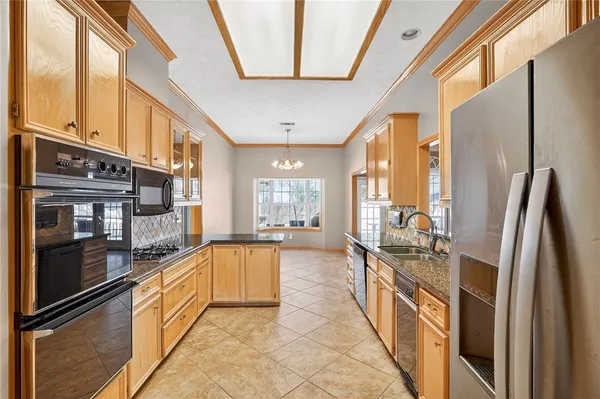 a large open kitchen with stainless steel appliances granite countertop a refrigerator a oven and a stove next to a window