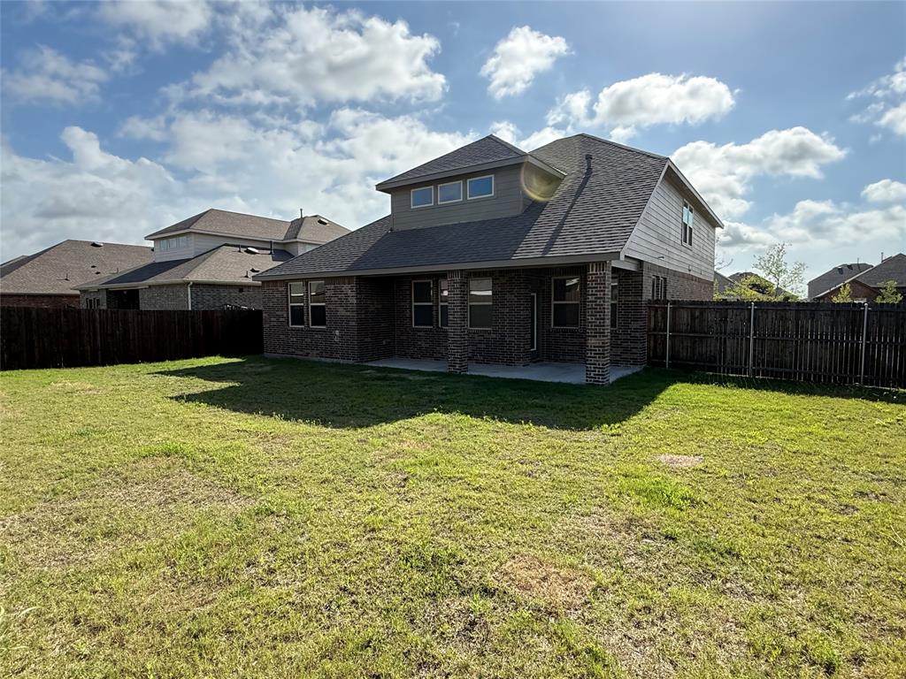 1306 Colonial Bluff Lane Princeton, TX 75407 - Photo 26 of 27 Expansive backyard featuring a covered patio, brick exterior, dark shingles, and a privacy fence