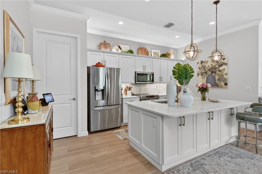 14628 Kingfisher Loop Naples, FL 34120 - Photo 12 of 39 a kitchen with stainless steel appliances granite countertop a refrigerator a sink dishwasher and white cabinets with wooden floor