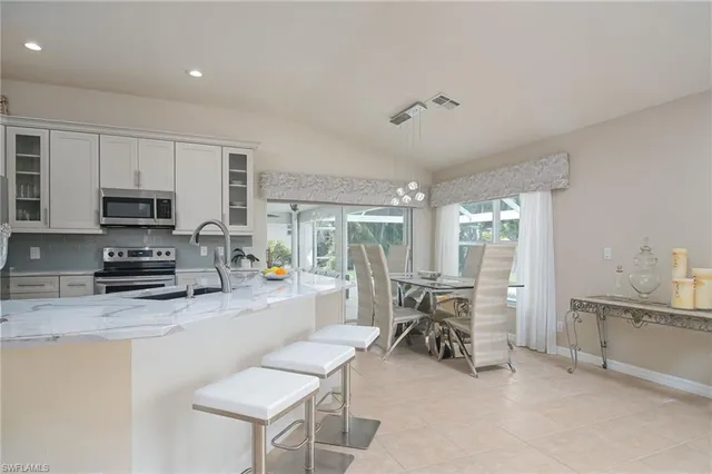 a kitchen with stainless steel appliances a white table chairs and a refrigerator