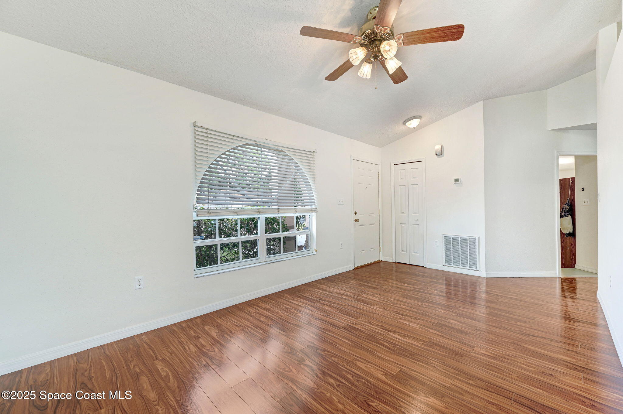 6094 Cardiff Avenue Cocoa, FL 32927 - Photo 11 of 48 an empty room with wooden floor chandelier fan and windows