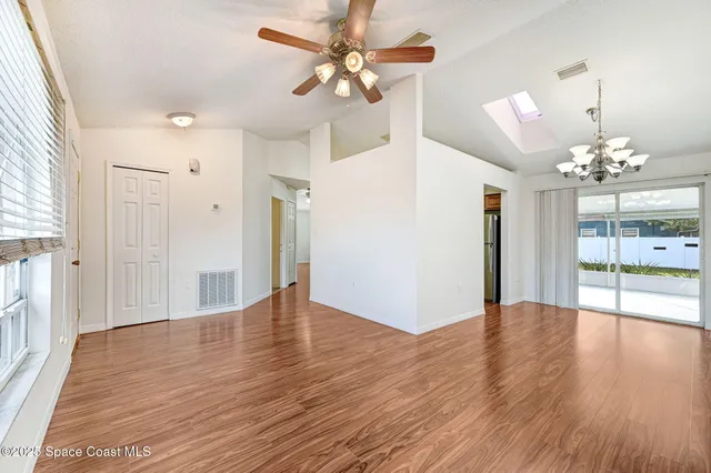 a view of an empty room with window and wooden floor