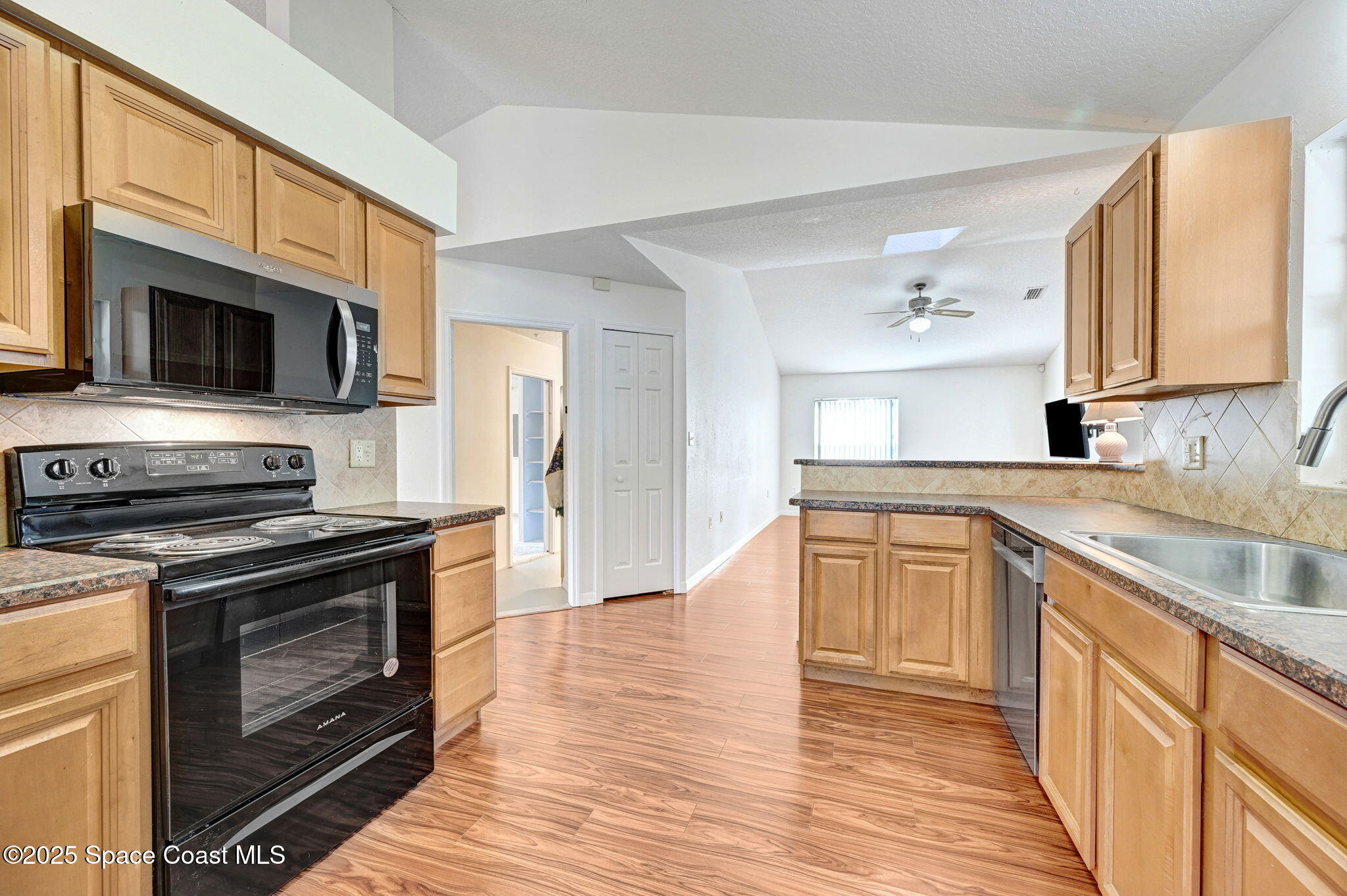 6094 Cardiff Avenue Cocoa, FL 32927 - Photo 14 of 48 a kitchen with stainless steel appliances granite countertop a stove top oven a sink dishwasher a microwave oven and a refrigerator with wooden floor