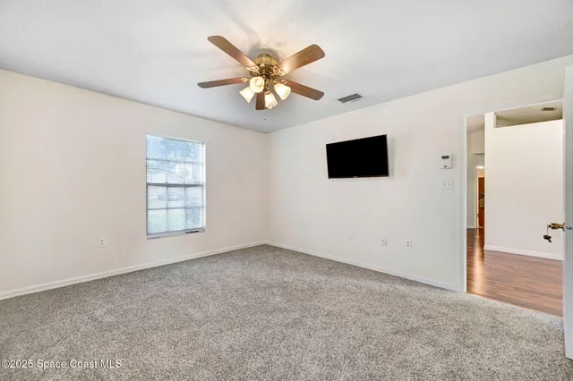 an empty room with windows and fan