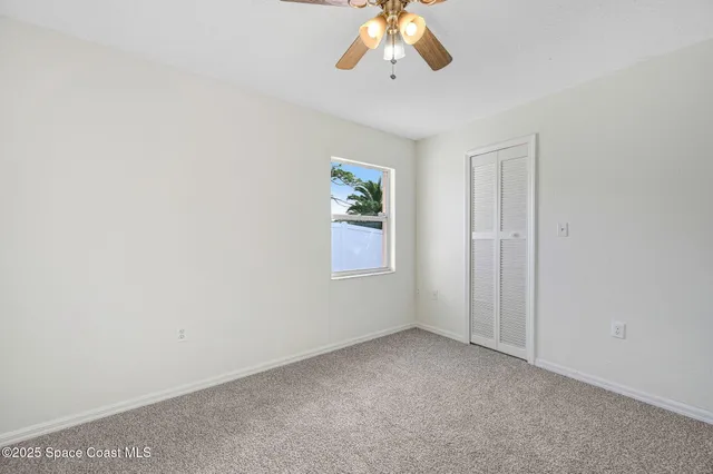 an empty room with a window and a ceiling fan