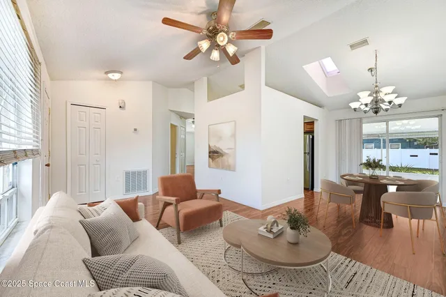 a living room with furniture a chandelier and a dining table