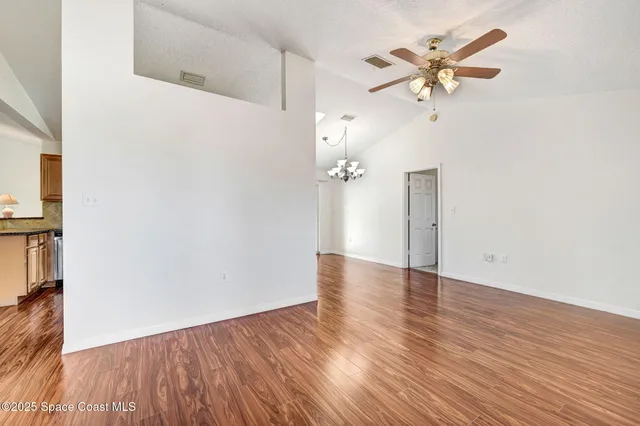 an empty room with wooden floor and ceiling fan
