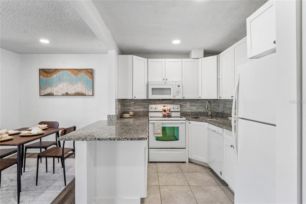 2522 Pine Ridge Way South, Unit D2 Palm Harbor, FL 34684 - Photo 11 of 38 a kitchen with stainless steel appliances granite countertop a refrigerator and a stove top oven