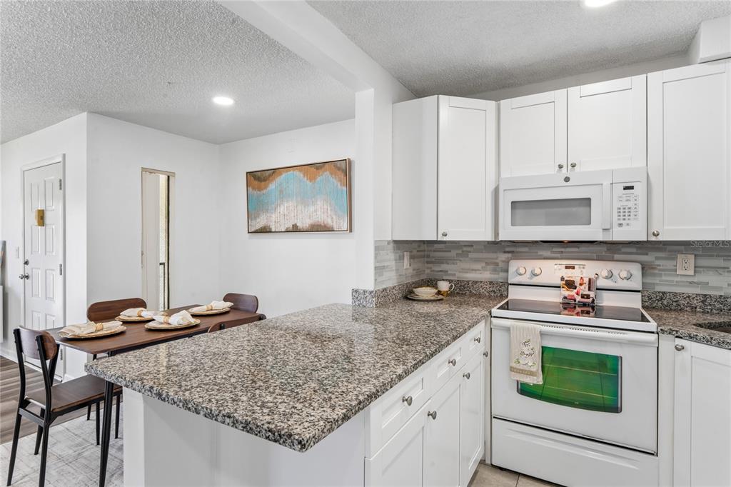 2522 Pine Ridge Way South, Unit D2 Palm Harbor, FL 34684 - Photo 14 of 38 a kitchen with stainless steel appliances granite countertop a stove sink and cabinets