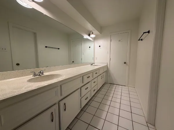 a spacious bathroom with a double vanity sink a mirror and a