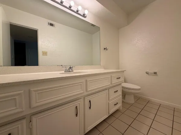 a bathroom with a granite countertop sink a toilet and a mirror