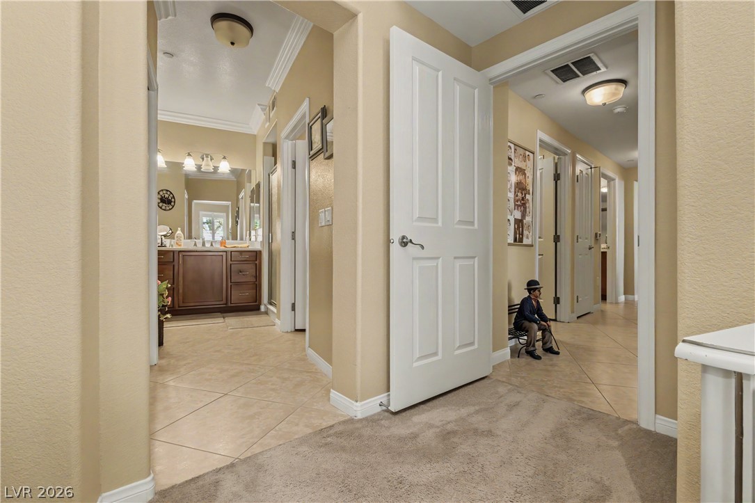 2555 Hampton Road, Unit 3308 Henderson, NV 89052 - Photo 37 of 65 A warm and inviting hallway features a mix of plush carpeting and durable tile flooring, leading to a well-appointed bathroom.