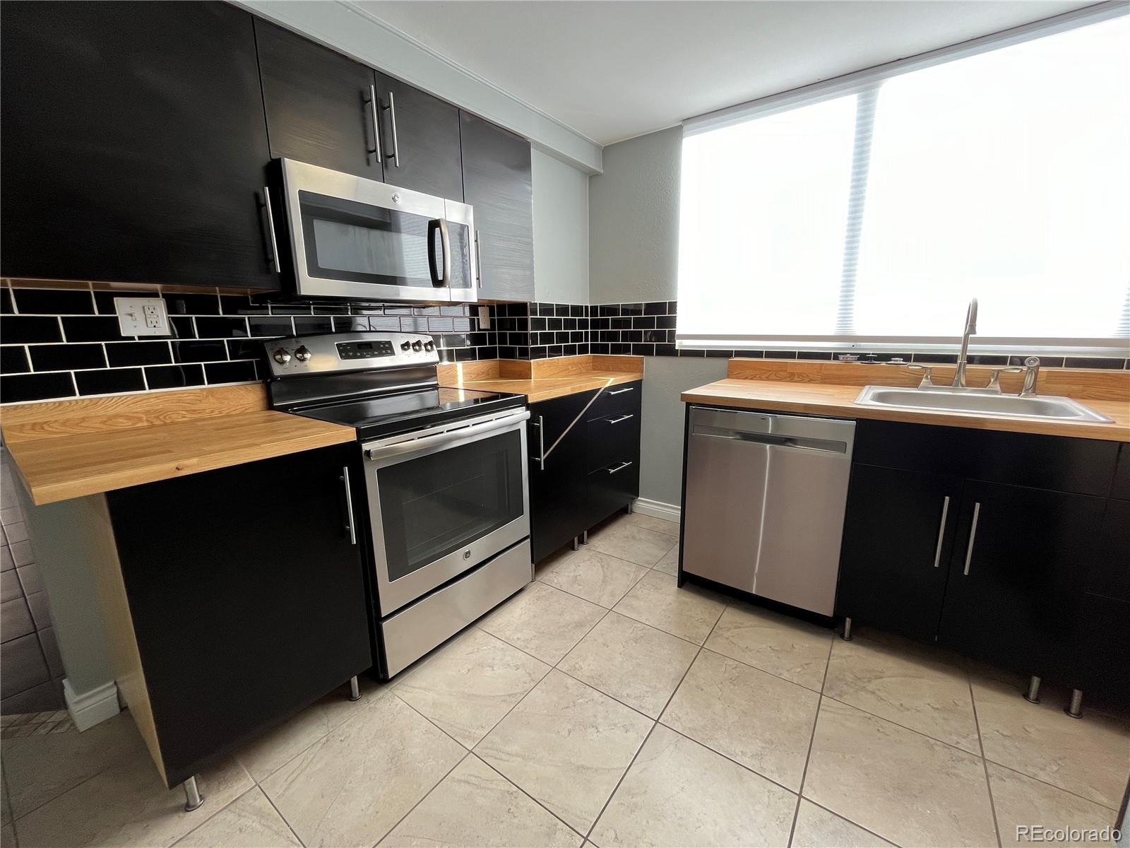 1155 Ash Street, Unit 202 Denver, CO 80220 - Photo 20 of 21 a kitchen with stainless steel appliances granite countertop a stove a sink and a microwave