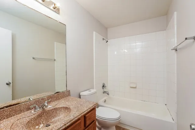 a bathroom with a granite countertop sink a toilet and shower