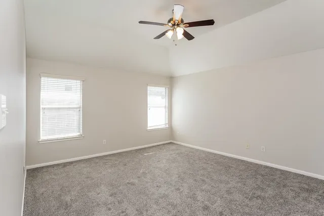 an empty room with windows and fan