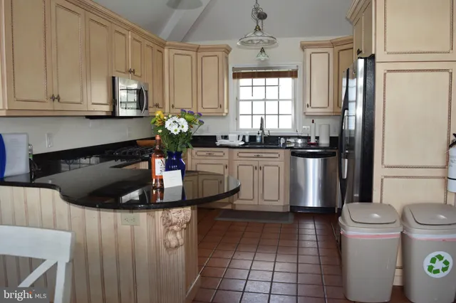 a kitchen with kitchen island granite countertop a sink a stove and refrigerator