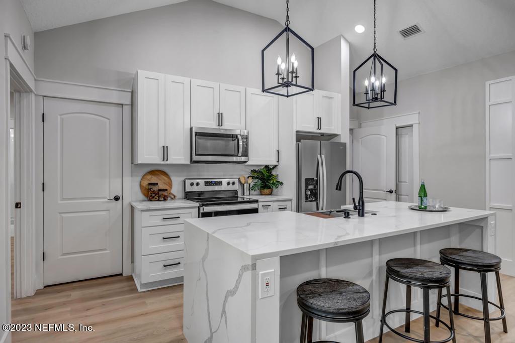 1281 Glen Laura Road Jacksonville, FL 32205 - Photo 7 of 33 a kitchen with stainless steel appliances a table chairs cabinets and wooden floor