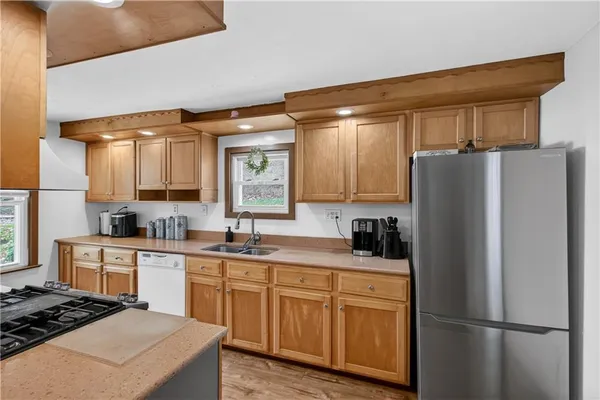 a kitchen with a refrigerator a sink dishwasher a stove and white cabinets with wooden floor