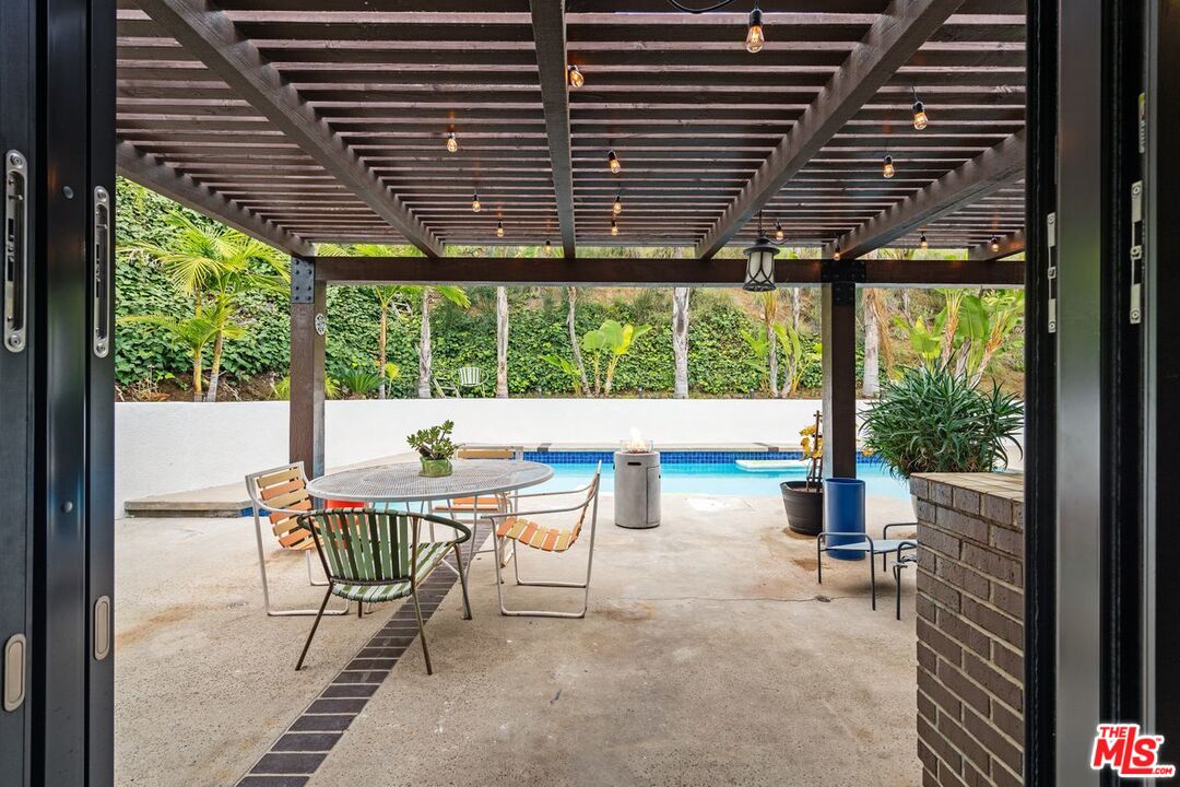 3135 Chandelle Road Los Angeles, CA 90046 - Photo 11 of 29 a view of a patio with a table and chairs and couches with wooden floor and fence