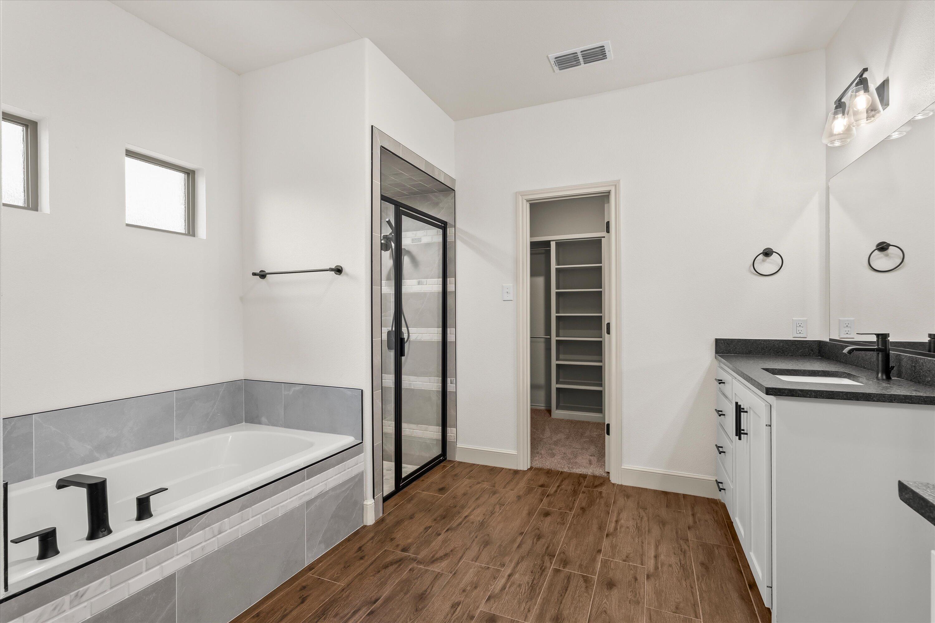 5719 116th Street Lubbock, TX 79424 - Photo 14 of 31 a bathroom with a granite countertop sink a bathtub and shower