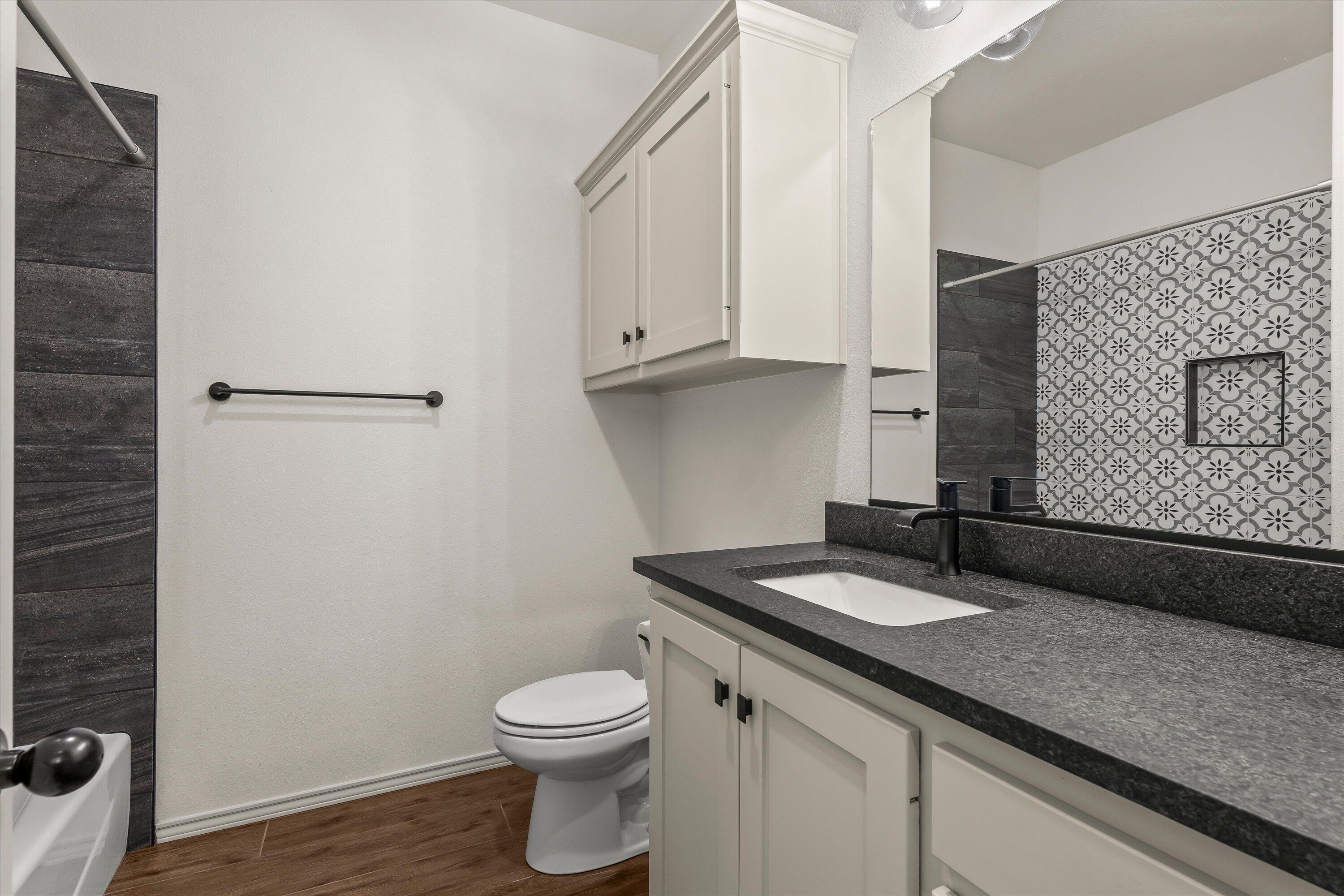 5719 116th Street Lubbock, TX 79424 - Photo 21 of 31 a bathroom with a granite countertop sink and a toilet