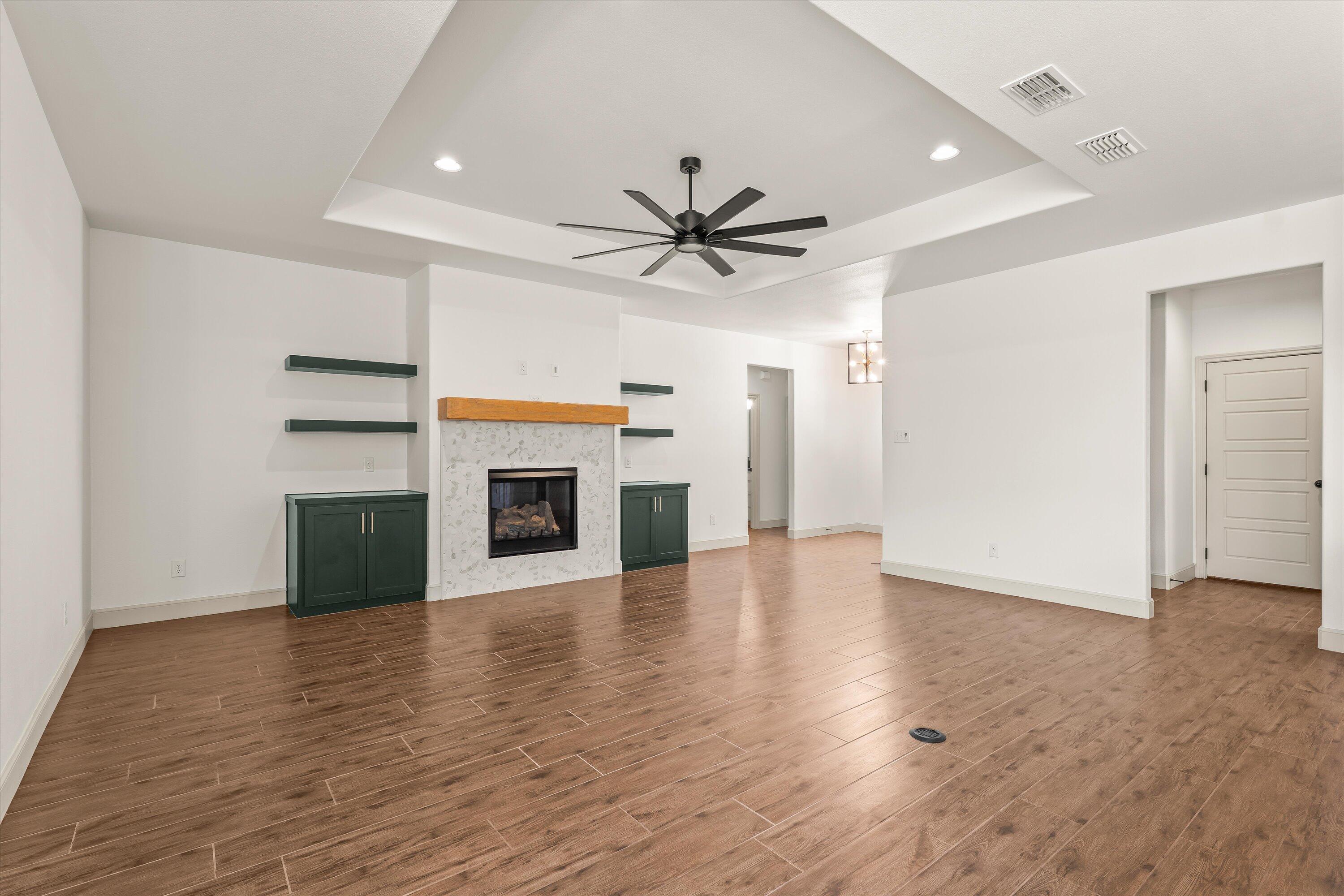 5719 116th Street Lubbock, TX 79424 - Photo 6 of 31 an empty room with a fireplace and a ceiling fan