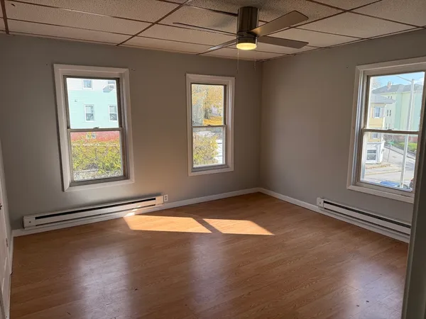 an empty room with wooden floor chandelier and windows