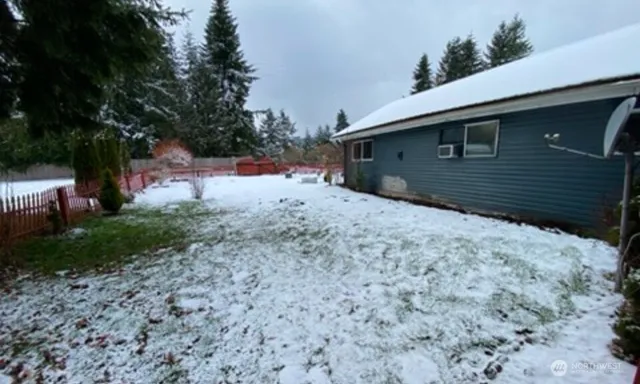 a backyard of a house with large trees and wooden fence