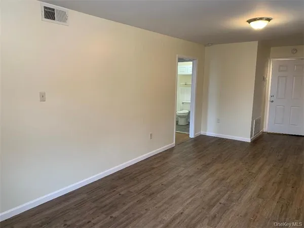 a view of an empty room with wooden floor and closet