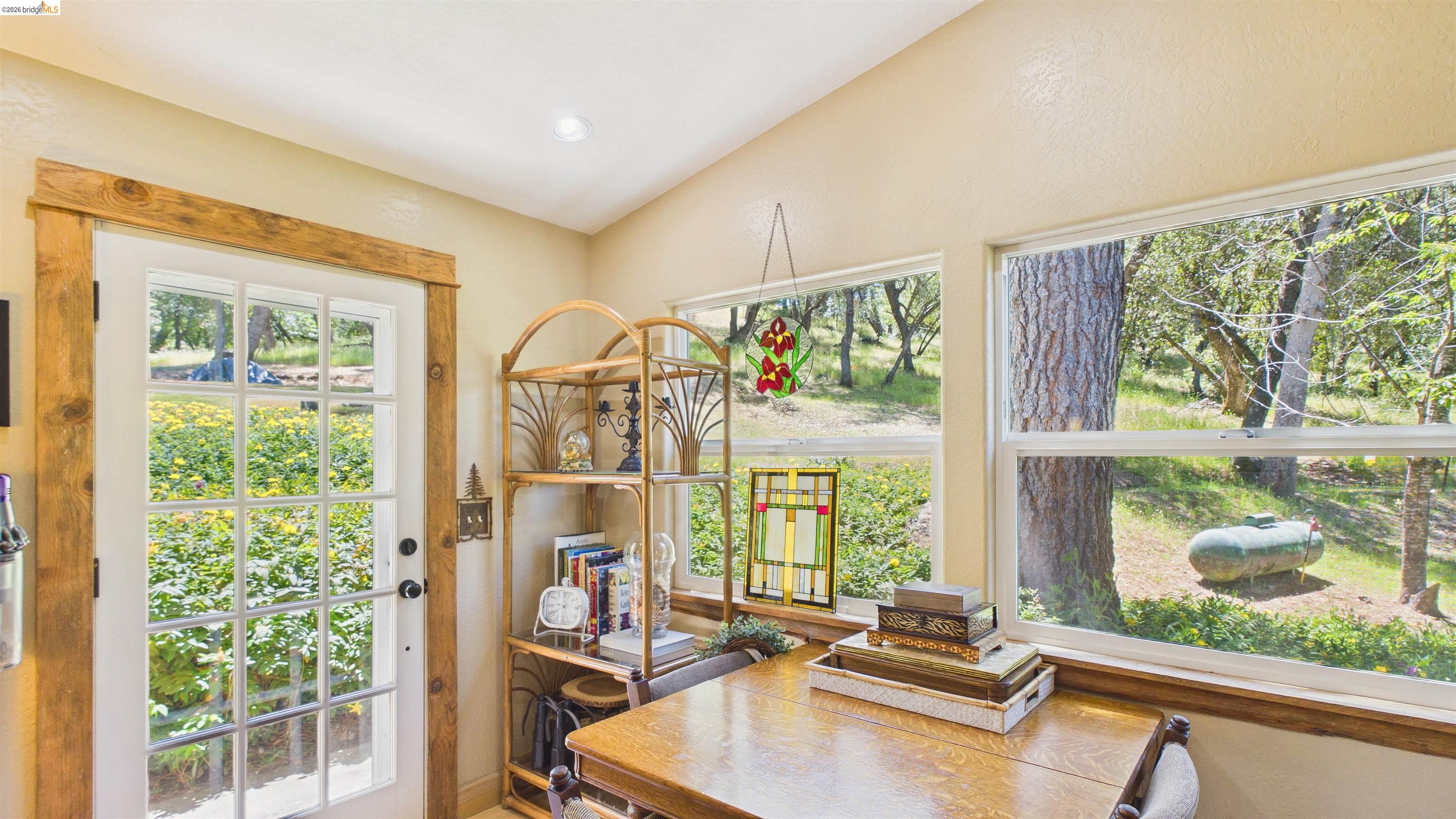 18102 Mt Eaton Road Tuolumne, CA 95379 - Photo 22 of 44 Natural light-filled room featuring a paneled glass door with rustic wood trim and two large windows