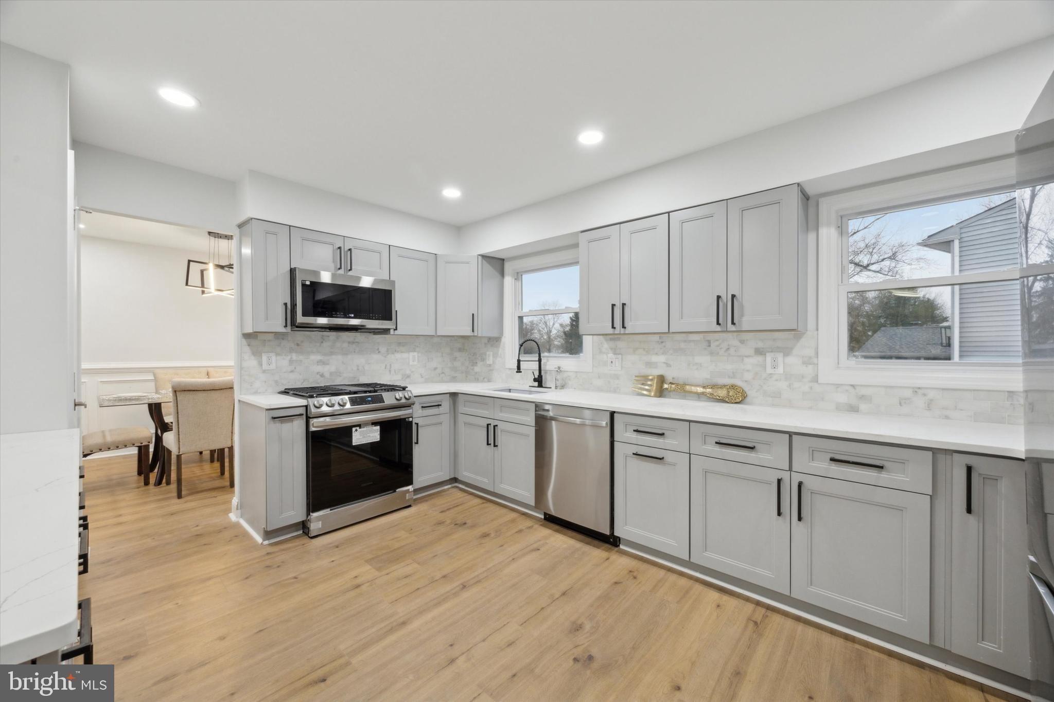 2124 Arleigh Road Cinnaminson, NJ 08077 - Photo 9 of 31 a kitchen with stainless steel appliances granite countertop a stove top oven a sink dishwasher and a refrigerator with wooden floor