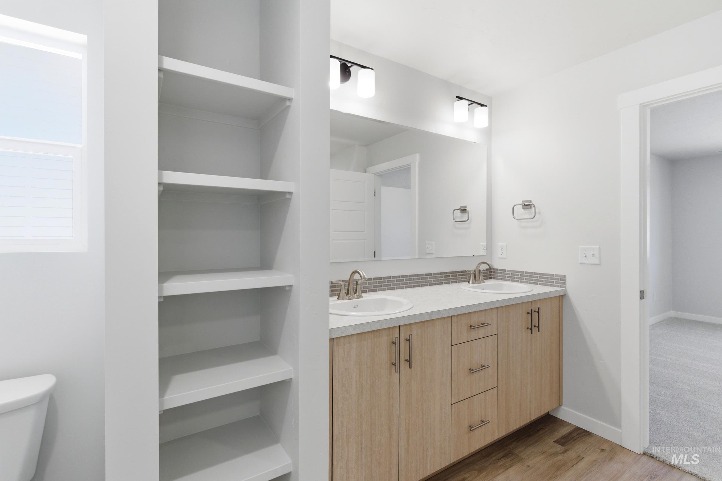 8317 South Tyrion Way Kuna, ID 83634 - Photo 20 of 22 Bathroom featuring a dual vanity with light wood-finish cabinetry, a light-toned countertop, and a tile backsplash