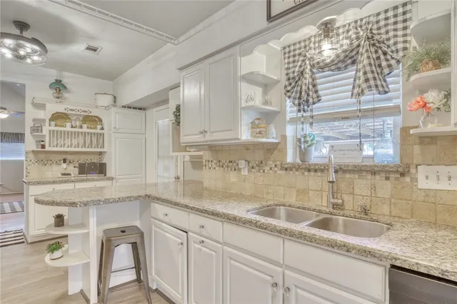 a kitchen with granite countertop a sink a window cabinets and stainless steel appliances