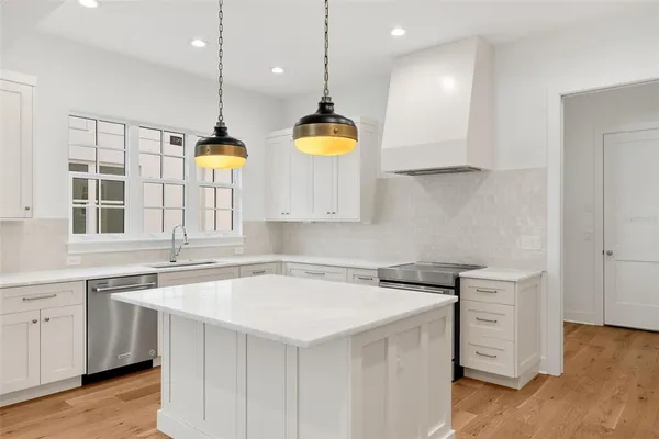a kitchen with a sink a stove a center island a window and cabinets