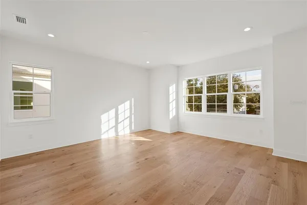 a view of an empty room with a window and wooden floor